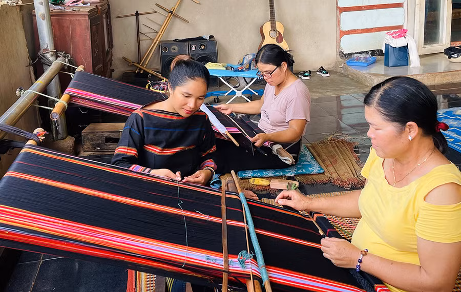 Chị H'thi (bìa trái) vận động chị em trong làng tham gia Tổ hợp tác dệt thổ cẩm với mục đích duy trì và phát triển nghề truyền thống. Ảnh: M.K