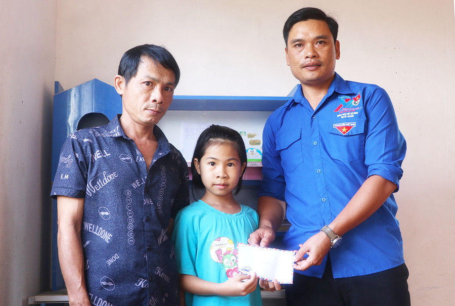 Anh Nguyễn Văn Minh-Bí thư Đoàn phường Tây Sơn (bìa phải) trao tiền hỗ trợ cho em Lê Thị Anh Thư (tổ 3). Ảnh: N.M