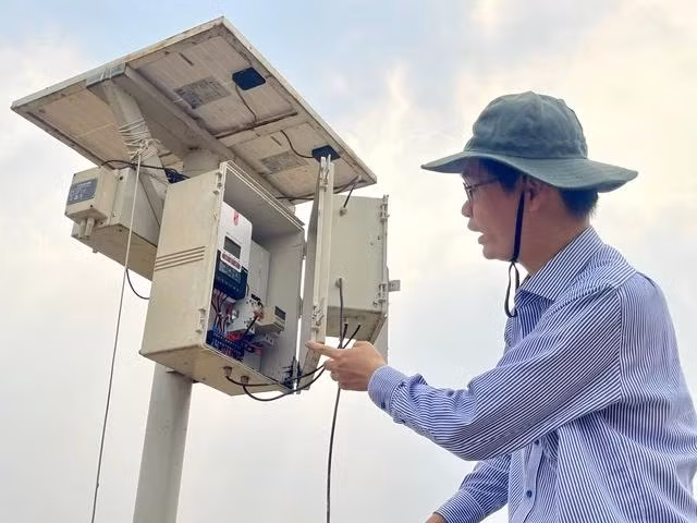 PGS.TS Phạm Quốc Cường và thiết bị quan trắc trên đồng cỏ khu A5. Ảnh: Thụy Miên