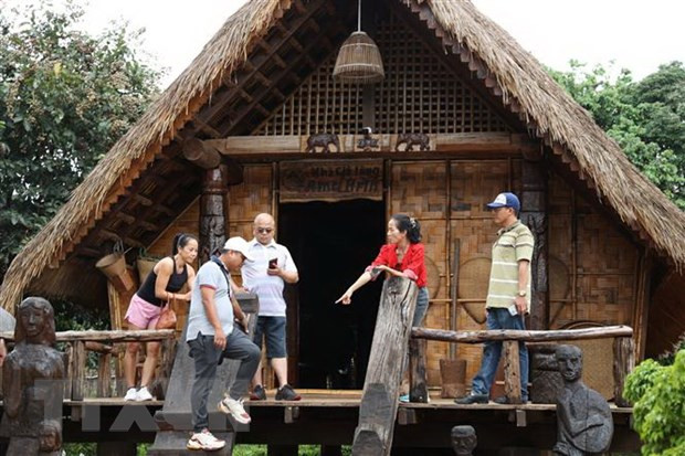 Du khách tìm hiểu kiến trúc nhà truyền thống của người Êđê tại Buôn AKô Đhông, thành phố Buôn Ma Thuột. (Ảnh: Tuấn Anh/TTXVN)