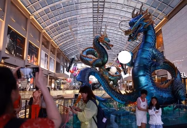 Người dân chụp ảnh với tác phẩm điêu khắc rồng tại một trung tâm mua sắm ở Singapore ngày 7.2