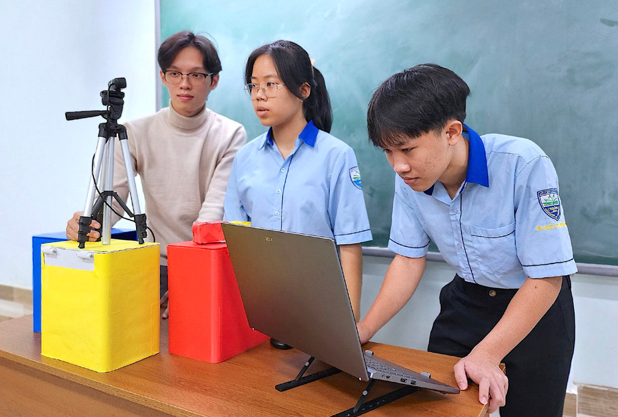 Thầy Trần Quốc Cường (bìa trái, giáo viên Tin học, Trường THPT Chi Lăng) hướng dẫn 2 em Nguyễn Thảo Uyên và Lê Văn Nam Khánh (lớp 10A7) thực hiện dự án chế tạo robot phân loại rác thải. Ảnh: M.T