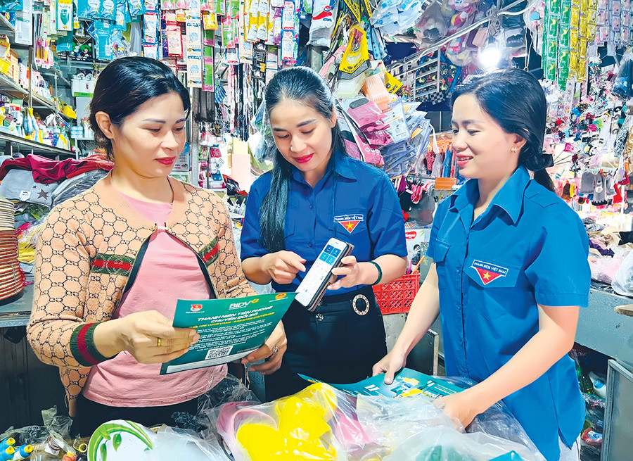 Đoàn viên, thanh niên phường Hoa Lư (TP. Pleiku) hướng dẫn tiểu thương cài đặt mã QR. Ảnh: T.B