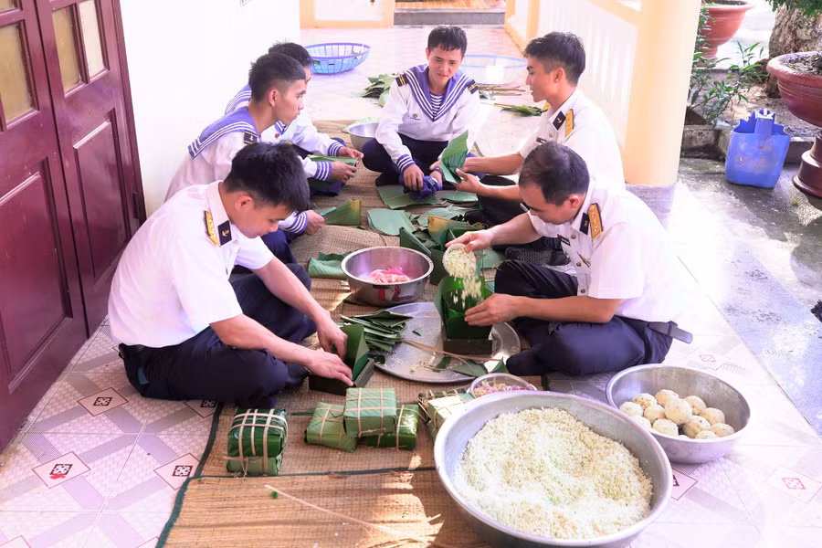 Cán bộ đảo Sinh Tồn hướng dẫn chiến sĩ trẻ thực hành gói bánh chưng. Ảnh: Phan Ngọc Đức