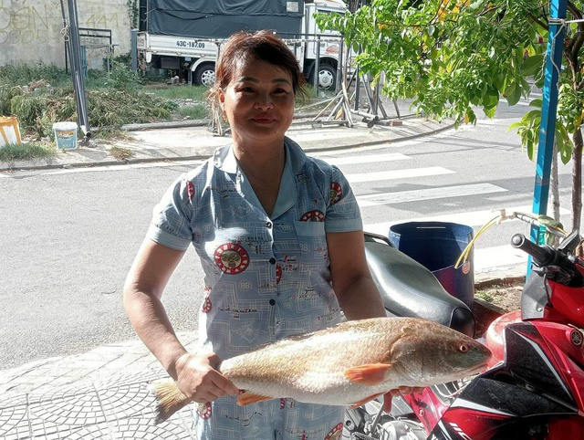 Chị Lê Thị Tiến và con cá sủ vàng. Ảnh: NGUYỄN TÚ