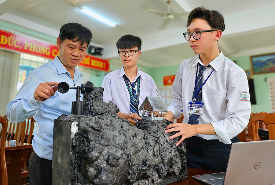 Hai em Ngô Hữu Gia Phước (bìa phải) và Nguyễn Mai Quang Minh hoàn thiện sản phẩm Safe Alert cùng với giáo viên hướng dẫn. Ảnh: M.T