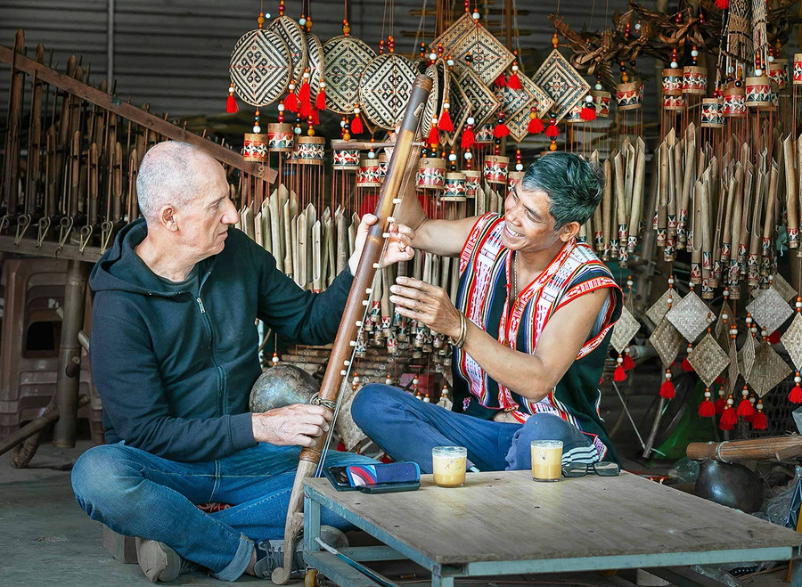 Du khách người Ý thích thú tìm hiểu các nhạc cụ truyền thống Jrai dưới sự hướng dẫn của Nghệ nhân Ưu tú Rơ Châm Tih. Ảnh: Nguyễn Linh Vinh Quốc