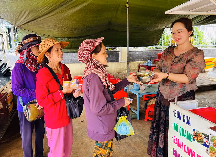 Chị Trần Thị Giáng Sinh (bìa phải) trao các suất “cơm treo” cho những người có hoàn cảnh khó khăn. Ảnh: M.N