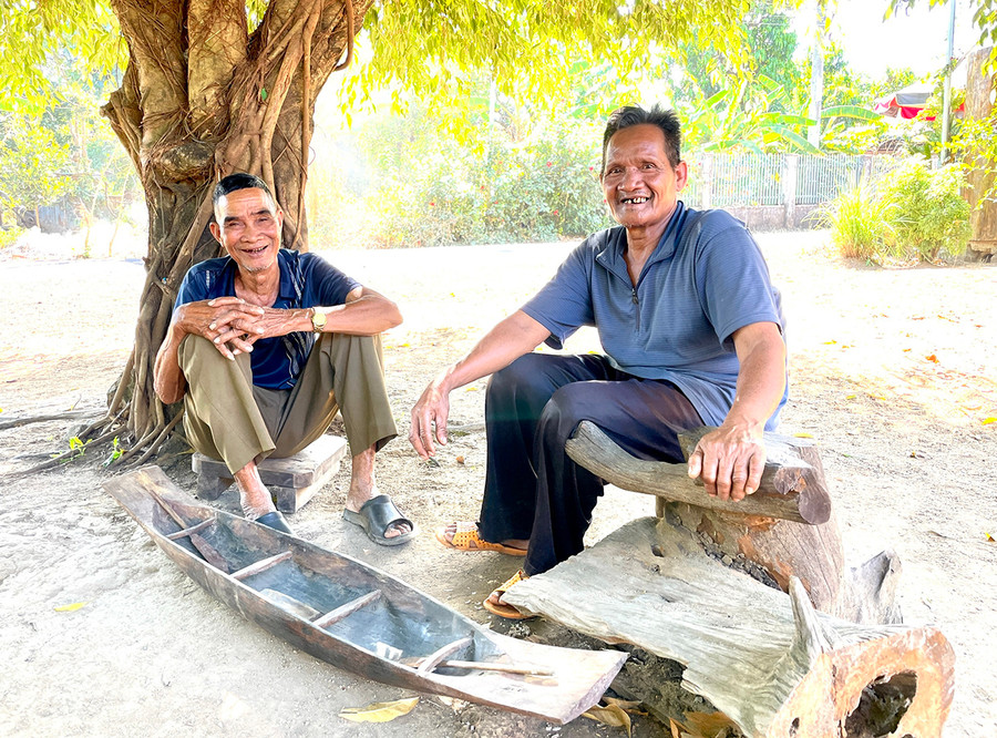 Già Pêng (bìa trái) và già Hmơnh bên chiếc thuyền độc mộc thu nhỏ. Ảnh: P.D