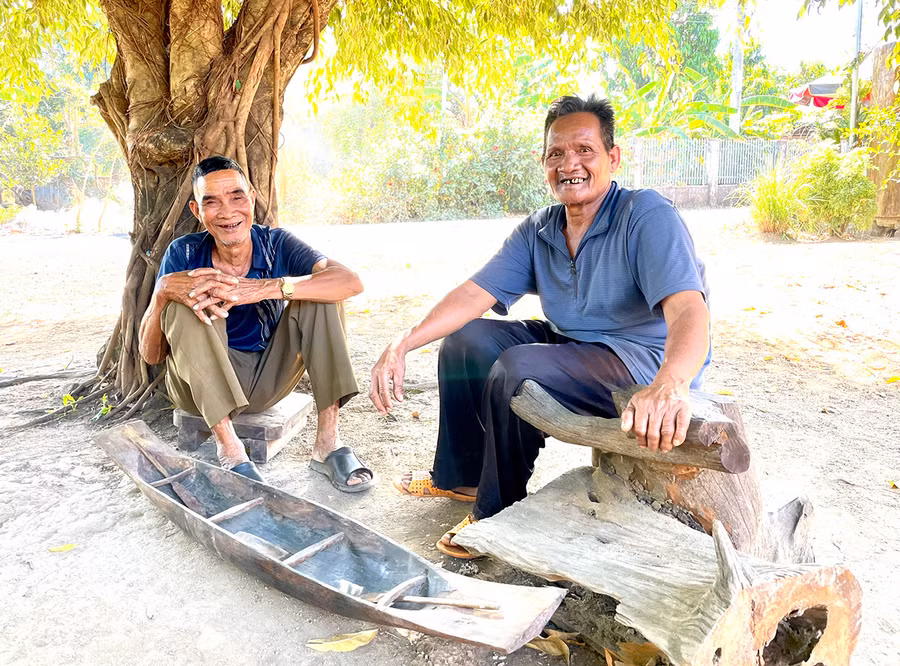 Già Pêng (bìa trái) và già Hmơnh bên chiếc thuyền độc mộc thu nhỏ. Ảnh: P.D