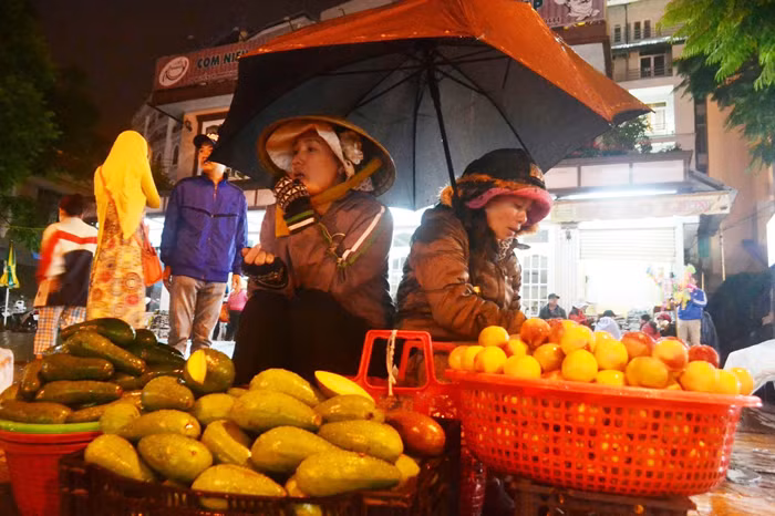 Người buôn bán nhỏ lẻ ở “chợ âm phủ” co ro trong đêm mưa.