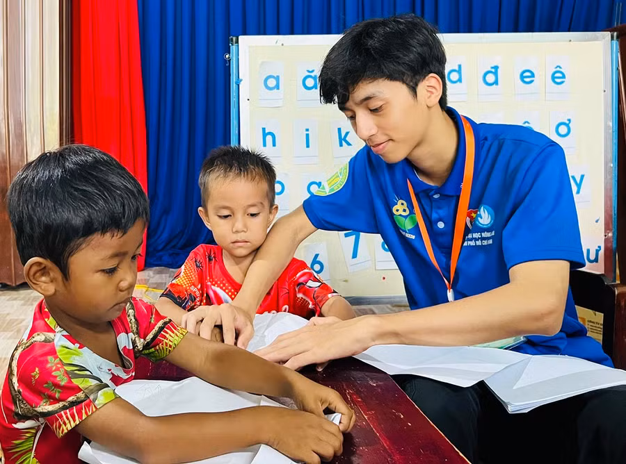 Sinh viên Trường Đại học Nông lâm TP. Hồ Chí Minh hướng dẫn thiếu nhi xã Ayun Hạ (huyện Phú Thiện) cách làm máy bay bằng giấy. Ảnh: P.L