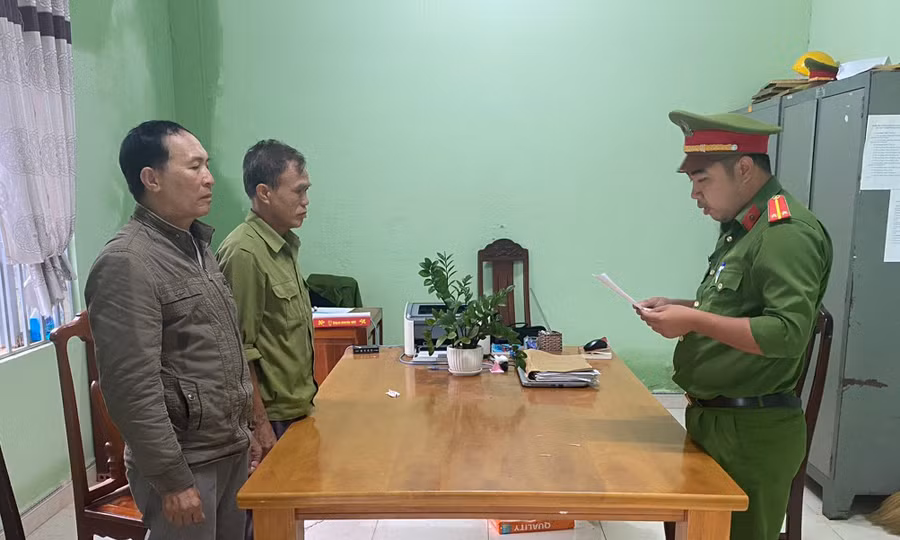 Phạm Thế Khiêm (bên trái, áo xám nâu) và Nguyễn Văn Nam nghe đọc lệnh khởi tố