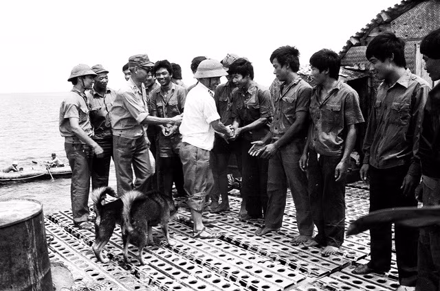 Đại tá Nguyễn Trung Cang (áo trắng) thăm hỏi, động viên bộ đội đảo Thuyền Chài trên nhà cao chân, 5.1988. Ảnh: Nguyễn Viết Thái