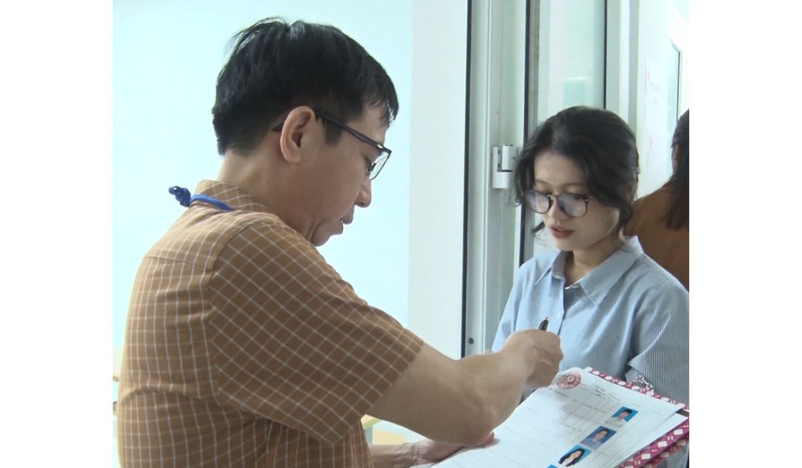 Cán bộ coi thi kiểm tra thông tin thí sinh trước khi vào phòng thi. Ảnh: Bá Bính