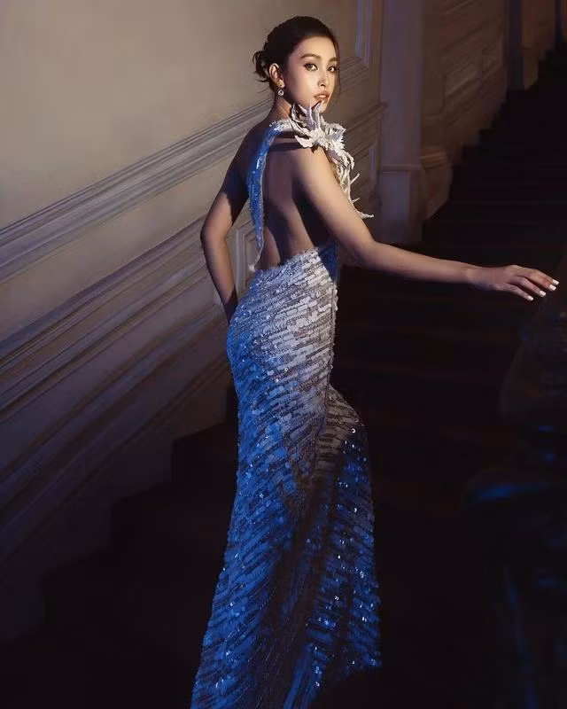 Cô nàng đã chọn lựa một bộ trang phục suông dài, được tinh tế, tạo ra một hiệu ứng thị giác độc đáo và nổi bật. Với vai áo bất đối xứng và phần hở lưng sâu, Tiểu Vy đã tạo nên một vẻ ngoài quyến rũ và đầy cuốn hút.