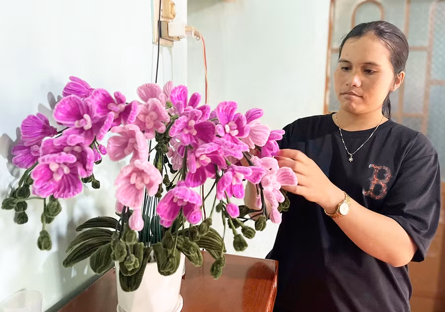 Chị H'Thoi tự đan móc những bông hoa bằng len để trang trí phòng khách của gia đình. Ảnh: P.D