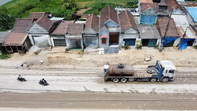 Nhiều ngôi nhà ven QL19 phải phủ bạt che chắn vì bụi bặm. Ảnh: THANH QUÂN