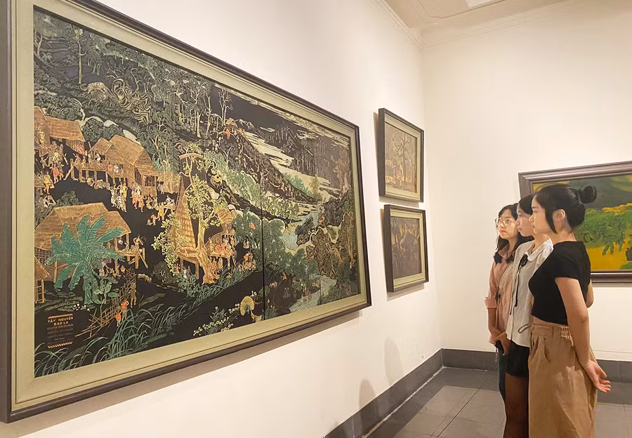 Khách thưởng lãm tác phẩm “Tây Nguyên bao la” của anh em họa sĩ Nguyễn Như Hoành và Nguyễn Như Huân. Ảnh: Lan Anh