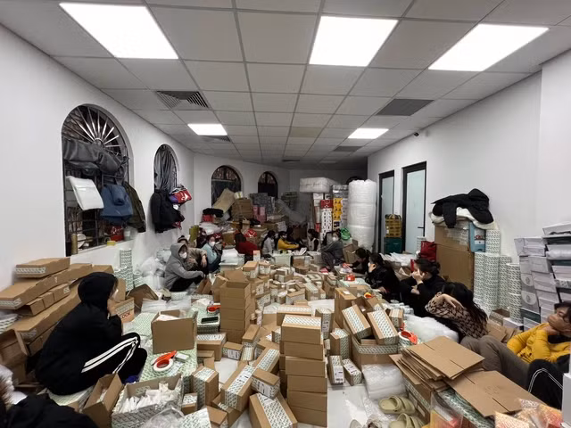 Hàng chục nhân viên đang đóng gói hàng để chuyển đi bên trong kho.