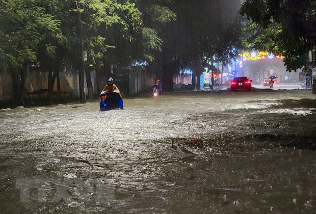 Người và phương tiện giao thông di chuyển khó khăn trên đoạn đường ngập sâu ở thành phố Điện Biên Phủ. (Ảnh: Xuân Tư/TTXVN)