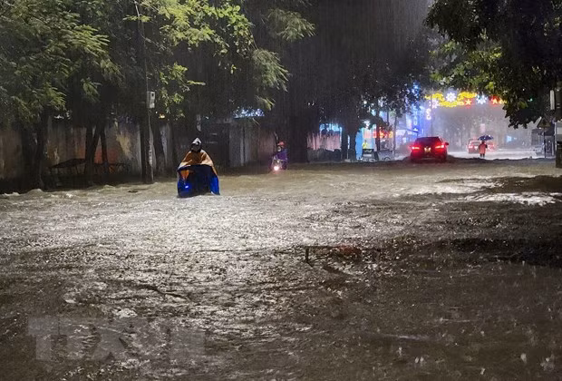 Người và phương tiện giao thông di chuyển khó khăn trên đoạn đường ngập sâu ở thành phố Điện Biên Phủ. (Ảnh: Xuân Tư/TTXVN)