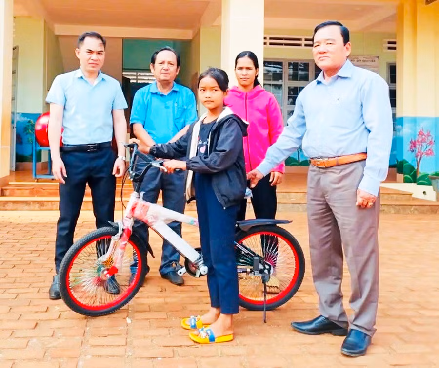 Chủ tịch Hội Khuyến học huyện Chư Sê Dương Chí Nghĩa (bìa phải) cùng cán bộ Hội tặng xe đạp cho học sinh nghèo. Ảnh: H.T