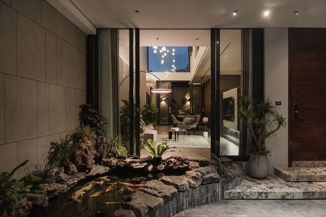 Tấm cửa kính lớn giúp người bên trong phòng khách có thể nhìn trực tiếp ra bể cá và cảnh quan bên ngoài.