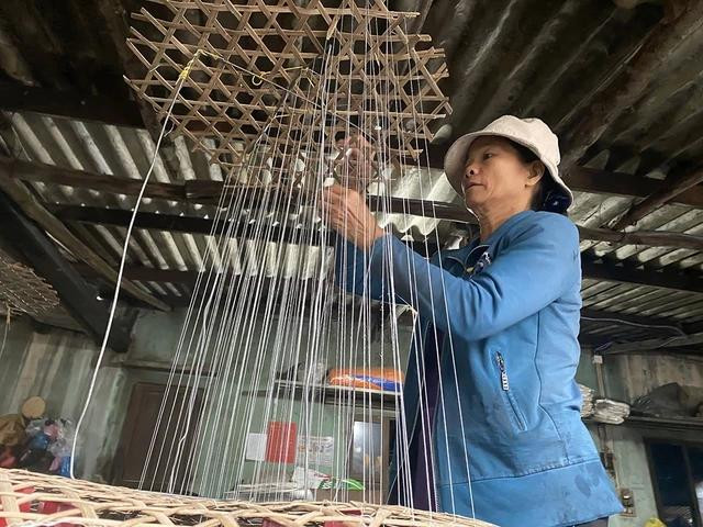 Bà Bùi Thị Anh Tuấn đang làm công đoạn luồn chỉ tạo khung, những sợi chỉ này đóng vai trò rất quan trọng trong công đoạn làm đường phèn. Ảnh: HẢI PHONG