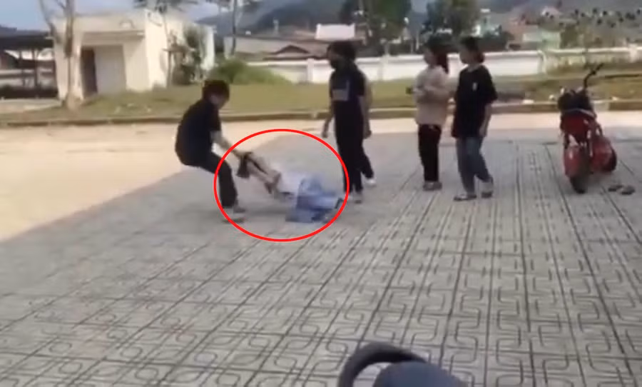 Nữ sinh bị túm tóc kéo lê trên sân gạch. Ảnh chụp lại từ video