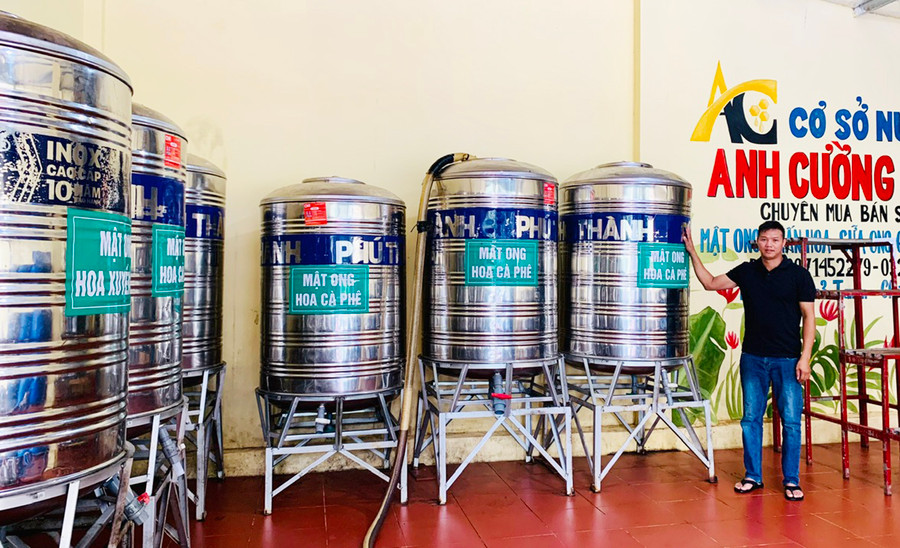 Anh Trần Văn Cường bên các bồn chứa mật ong tại cơ sở chế biến của gia đình. Ảnh: N.H Anh Trần Văn Cường bên các bồn chứa mật ong tại cơ sở chế biến của gia đình. Ảnh: N.H