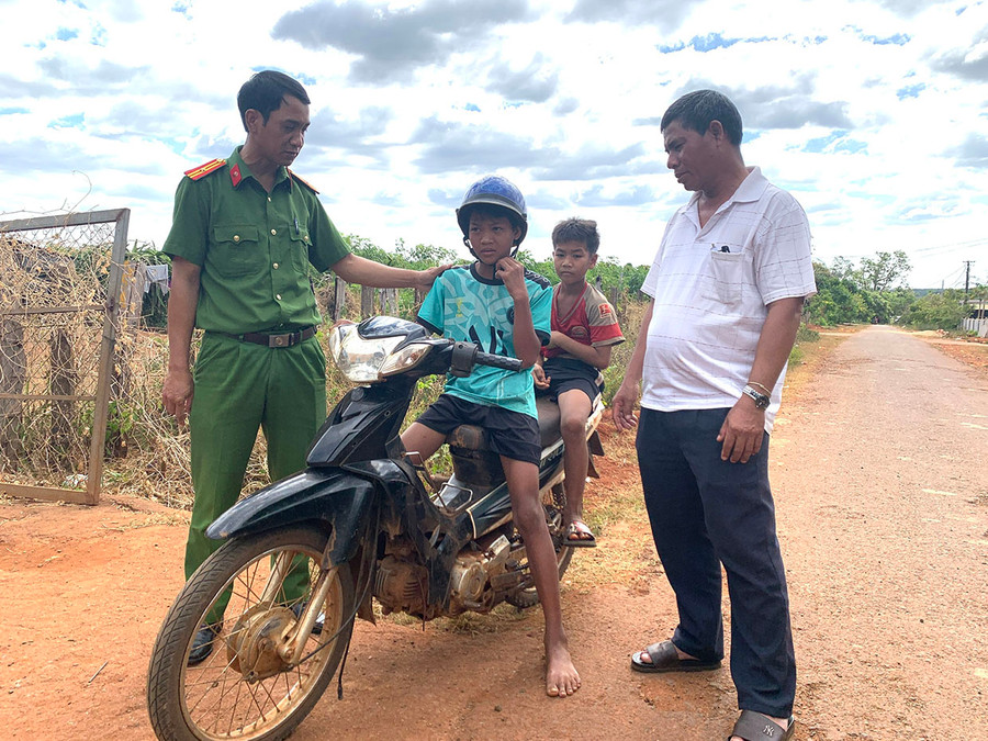 Thành viên mô hình liên kết các nhóm họ tự quản đảm bảo về an ninh trật tự làng Trol Đeng phối hợp với Công an thị trấn Chư Ty nhắc nhở em nhỏ về việc điều khiển xe máy khi chưa đủ tuổi là vi phạm pháp luật. Ảnh: R&apos;Ô HOK