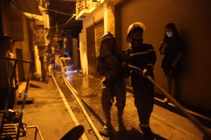 Do chung cư mini nằm sâu trong ngõ nên các chiến sĩ cảnh sát PCCC phải kéo ống phun nước vào. Ảnh: CTV