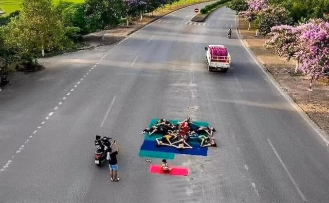 Nhóm người tụ tập trên đường quốc lộ rồi trải thảm cùng nhau tập yoga
