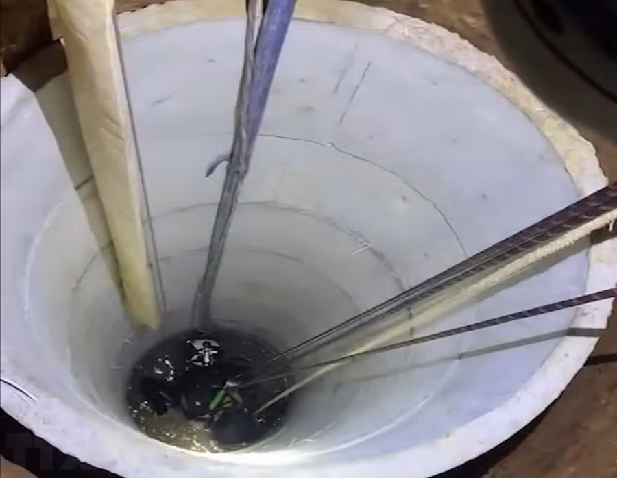 Lực lượng cứu hộ dùng dây cáp đưa thi thể anh Hiệp dưới giếng sâu lên bờ. (Ảnh: TTXVN phát)