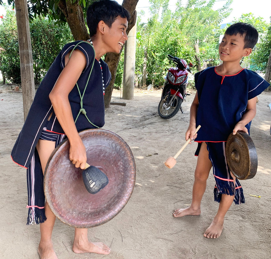Em Đinh Tuy (bìa trái) tập đánh cồng chiêng cùng bạn nhỏ trong làng. Ảnh: R.H