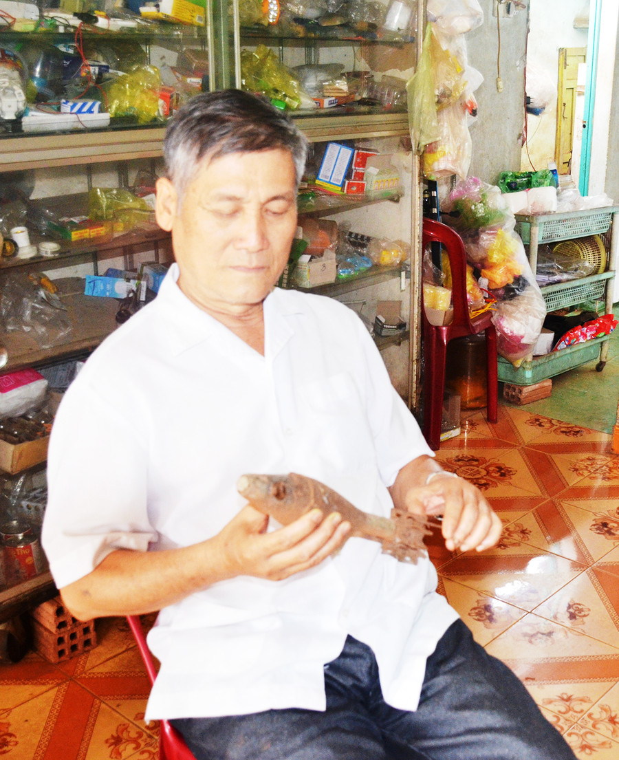 Cựu chiến binh Đoàn Khánh Tân và kỷ vật là quả đạn từng sử dụng để đánh địch. Ảnh: Vĩnh Hoàng