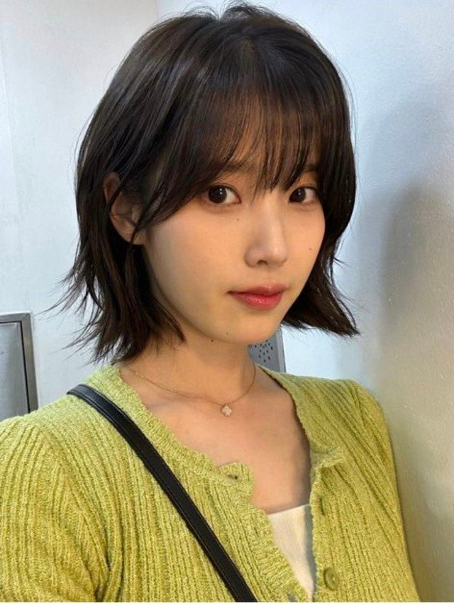 Lựa chọn kiểu tóc ngắn layer cắt tỉa nhiều lớp với phần đuôi hơi xòe cụp và tóc mái bằng lưa thưa, IU vẫn giữ được nét tươi tắn đặc trưng, bên cạnh đó là vẻ ngoài cá tính, hiện đại. Đây là kiểu tóc phù hợp với mọi gương mặt nhờ độ dài chạm tới xương quai xanh, không quá ngắn cũn cỡn hay kén dáng mặt