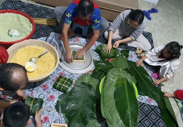 Gia đình quây quần gói bánh chưng, gạo được trộn với nước lá riềng tươi để khi bánh chín, phần gạo nếp luôn xanh mướt. ẢNH: BẢO VY