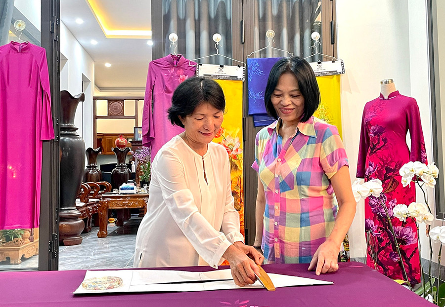 Bà Nguyễn Thị Hạnh (bìa trái) và bà Trần Thị Dung thực hành cắt may áo dài theo phương pháp ly vuông. Ảnh: L.N