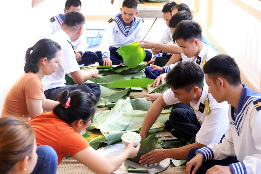 Các chị trong Hội phụ nữ xã đảo Sinh Tồn (H.Trường Sa, Khánh Hòa) tham gia gói bánh chưng với bộ đội đảo. Ảnh: Phan Ngọc Đức