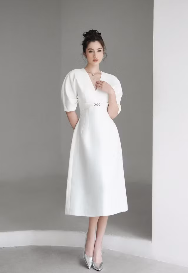 Không chỉ mang đến vẻ ngoài trung tính, thanh lịch và mới mẻ, váy dài tay phồng màu trắng với điểm nhấn tôn vòng 2, dáng cổ chữ V và tùng váy chữ A mang đến sự thoải mái cho nàng dù làm việc cả ngày