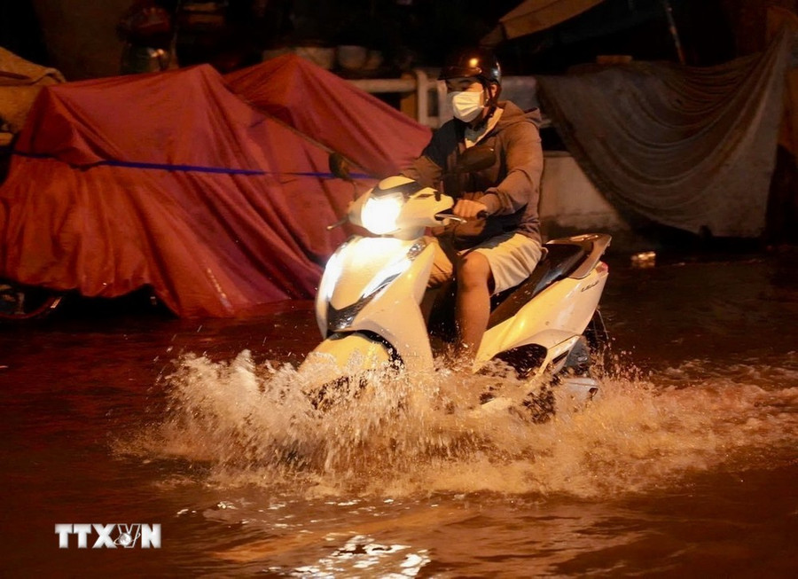 Người dân di chuyển giữa dòng nước ngập do triều cường trên đường Trần Xuân Soạn, quận 7. (Ảnh: TTXVN phát) Người dân di chuyển giữa dòng nước ngập do triều cường trên đường Trần Xuân Soạn, quận 7. (Ảnh: TTXVN phát)