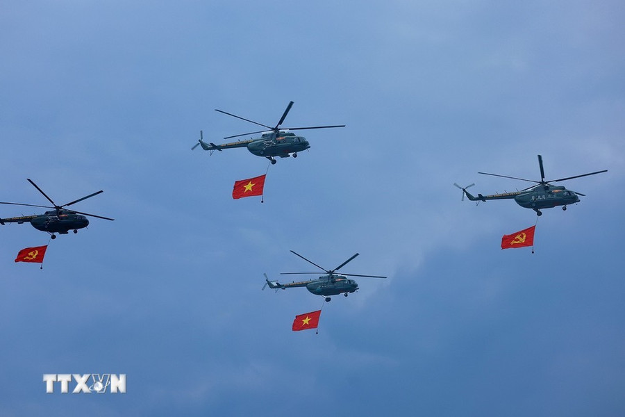 Máy bay trực thăng mang cờ Đảng, cờ Tổ quốc bay qua Lễ đài. (Ảnh: Dương Giang/TTXVN)