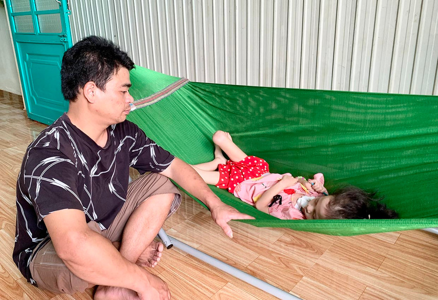 Anh Nguyễn Đức Phong chăm sóc con gái bị bệnh viêm não tủy lan tỏa. Ảnh: Như Nguyện