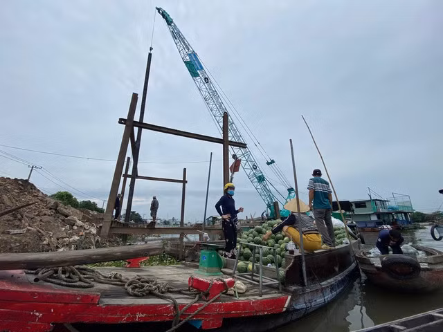 Ghe dưa hấu tấp vào chỗ trống của công trình bờ kè để lên hàng ở khu vực bến mù u xưa. Ảnh: LÊ VÂN