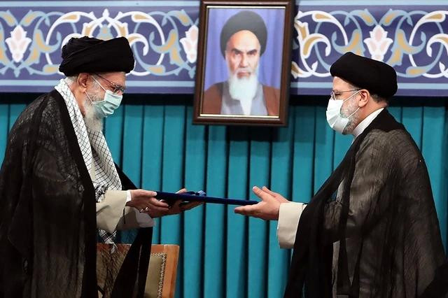 Lãnh tụ tối cao Ayatollah Ali Khamenei (trái) tại lễ nhậm chức của Tổng thống Ebrahim Raisi ngày 3.8.2021. Đằng sau là chân dung của cố Lãnh tụ tối cao Ayatollah Ruhollah Khomeini. Ảnh AFP Lãnh tụ tối cao Ayatollah Ali Khamenei (trái) tại lễ nhậm chức của Tổng thống Ebrahim Raisi ngày 3.8.2021. Đằng sau là chân dung của cố Lãnh tụ tối cao Ayatollah Ruhollah Khomeini. Ảnh AFP