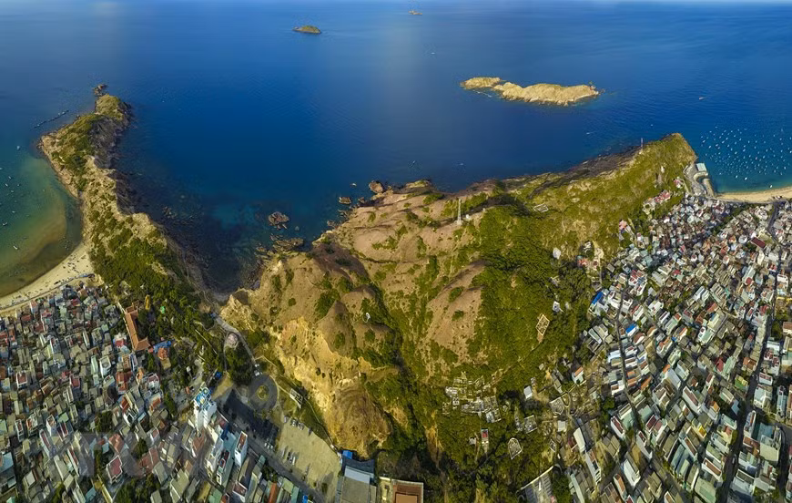 Nhìn từ xa, Eo Gió giống như một cái yên ngựa, nằm giữa hai mỏm núi cao kề bên biển, mặt khác nếu đứng từ trên cao nhìn xuống lại tựa như một cái phễu, vì thế Eo Gió luôn đón gió từ biển thổi vào với sức gió rất mạnh. (Ảnh: Minh Đức/TTXVN)