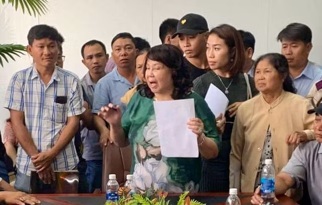 Bà Hiền (cầm giấy) trong một lần bị khách hàng tìm đến công ty đòi lại tiền mua đất. Ảnh: ĐÌNH SƠN