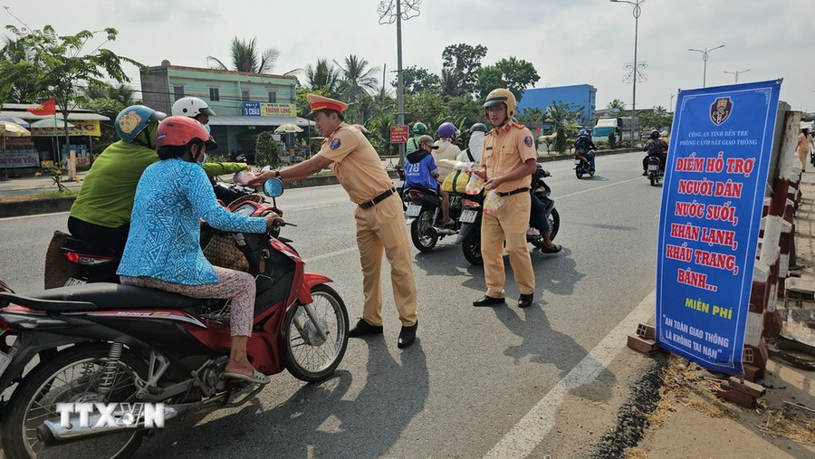 Cảnh sát giao thông Công an tỉnh Bến Tre phát nước miễn phí cho người dân. (Ảnh: Huỳnh Phúc Hậu/ TTXVN) Cảnh sát giao thông Công an tỉnh Bến Tre phát nước miễn phí cho người dân. (Ảnh: Huỳnh Phúc Hậu/ TTXVN)